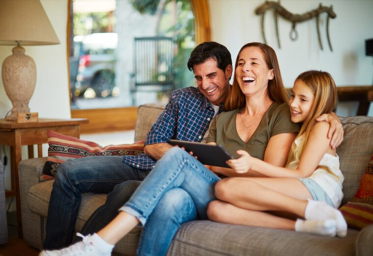 Familie genießt Zeit auf dem Sofa und informiert sich digital über Energieangebote