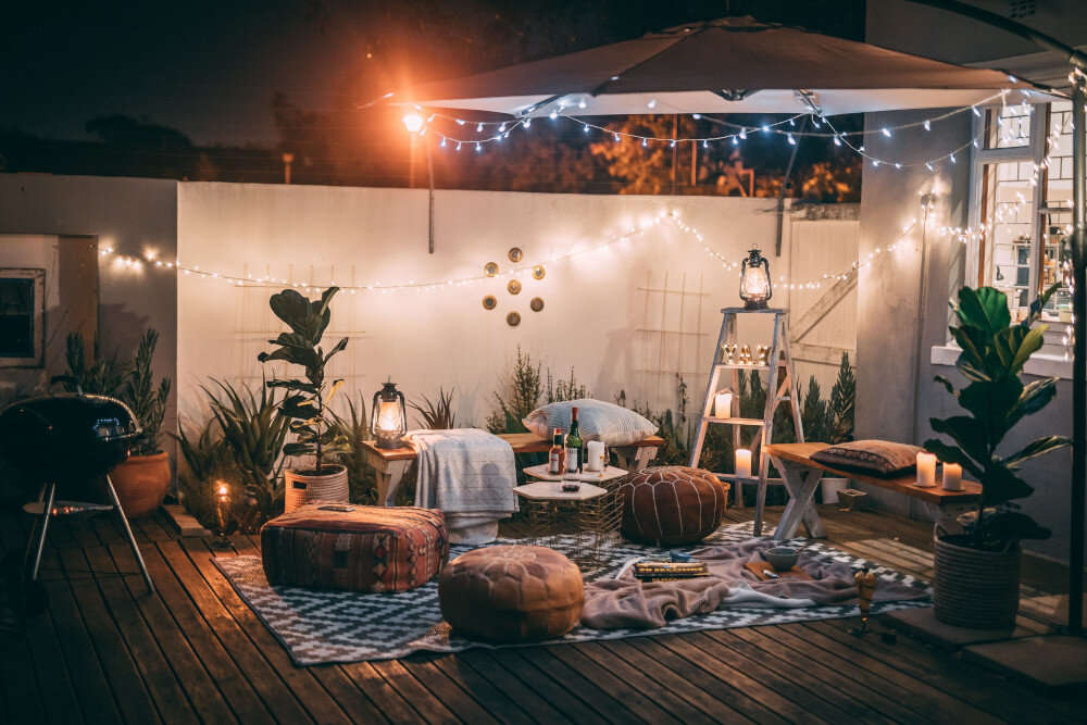 Terrasse mit Lichterketten, bequemen Möbeln und entspannter Atmosphäre bei Nacht