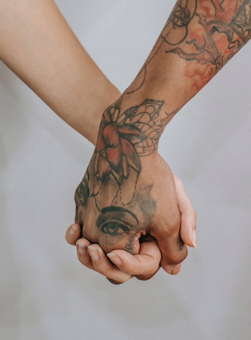 Zwei Menschen halten sich die Hände eng umschlungen. Fokus auf die Hände, eine davon ist tattoowiert.  | © pexels-tim-samuel-5845304