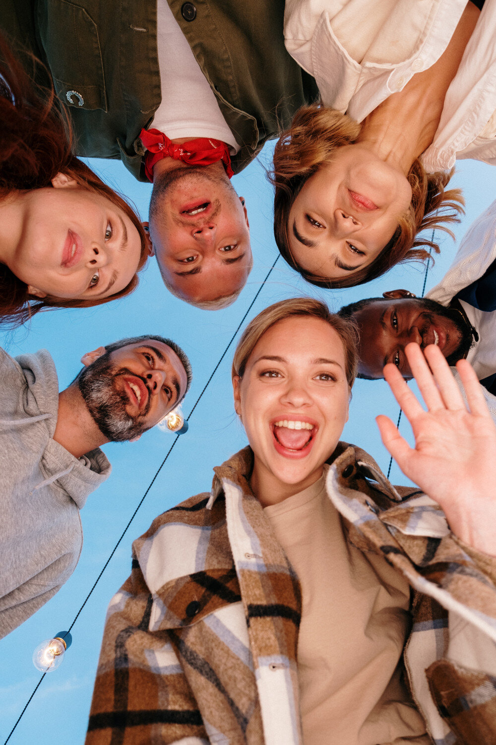 Freundesgruppe schaut von oben in die Kamera, manche winken, manche ziehen freudige Gesichter oder Grimassen. | © pexels-cottonbro-studio-4881619