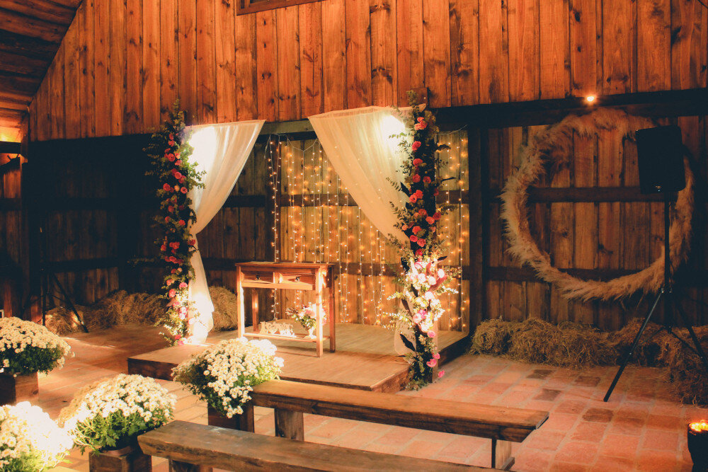 Beleuchteter Traualtar am Abend mit Sitzreihen für die Gäste. Romantisches, rustikales Hochzeitssetting. | © pexels-joel-paim-2434255