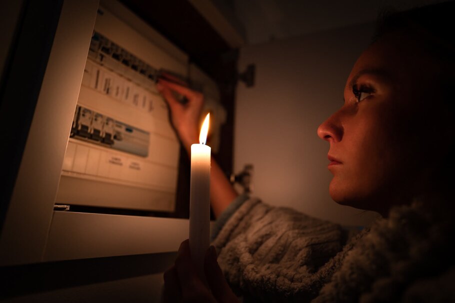 Frau prüft Stromkasten bei Kerzenlicht 