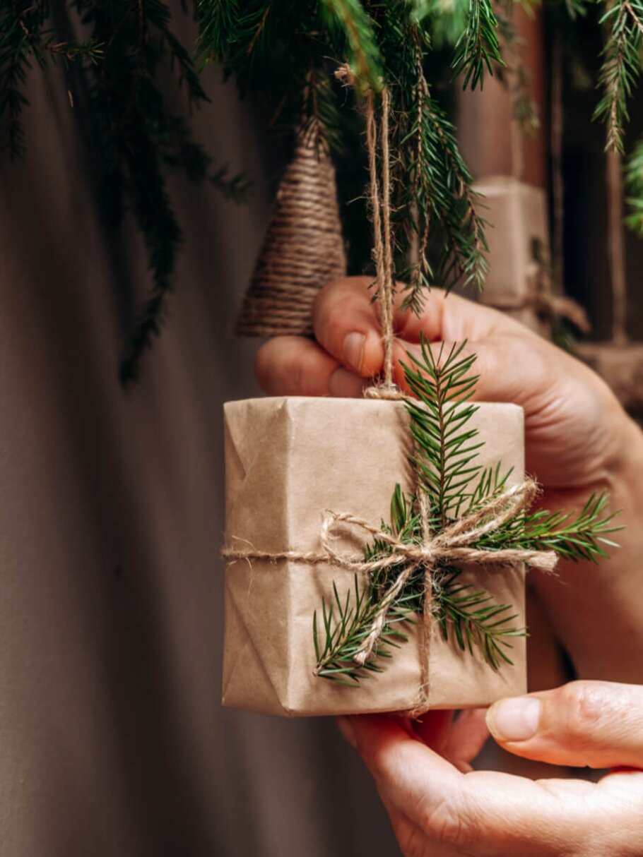 Frau hängt nachhaltige Weihnachtsdeko an den Weihnachtsbaum