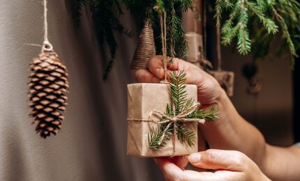 Frau hängt nachhaltige Weihnachtsdeko an den Weihnachtsbaum