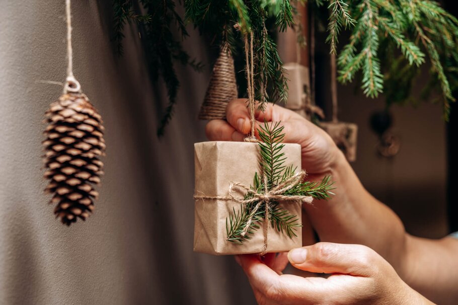 Frau hängt nachhaltige Weihnachtsdeko an den Weihnachtsbaum