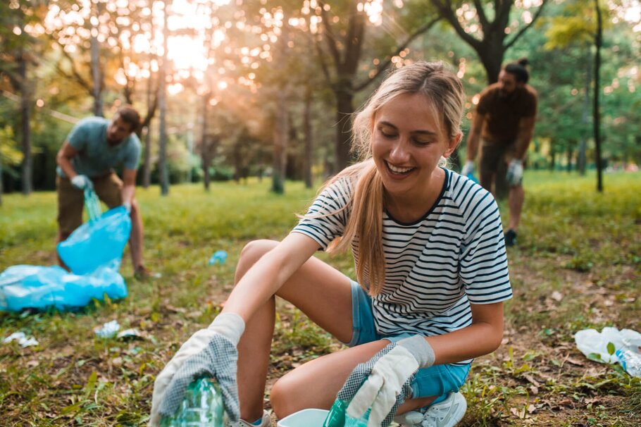 Junge Frau sammelt Plastikflaschen für Recycling ein