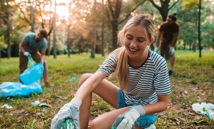 Junge Frau sammelt Plastikflaschen für Recycling ein