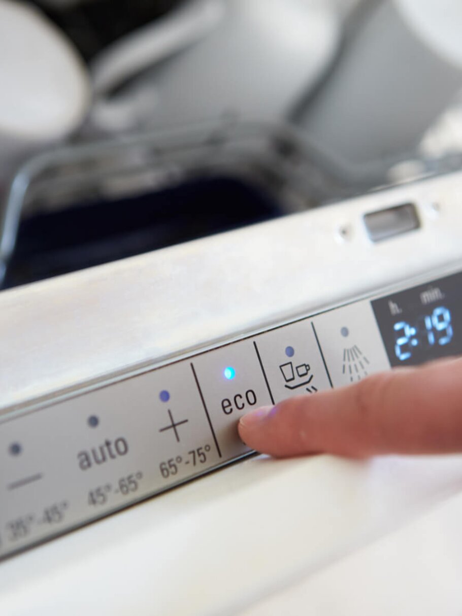 Mann betätigt ECO-Programm an der Spülmaschine