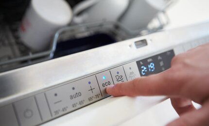 Mann betätigt ECO-Programm an der Spülmaschine