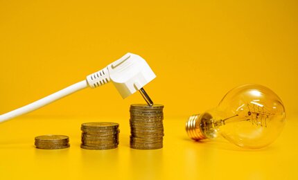 Glühbirne und Netzstecker vor gelbem Hintergrund