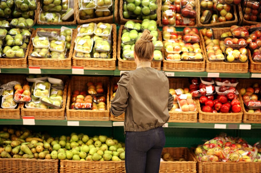 Frau vor Supermarktregal kauft Obst und Gemüse