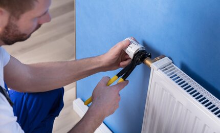 Handwerker-repariert-Heizung-mit-Rohrzange